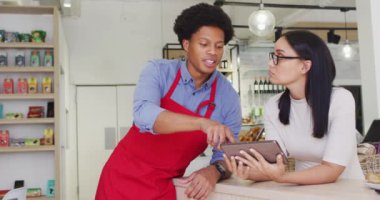 Video of happy diverse female owner and male waiter working with tabletat cafe shop. coffee and bistro shop, running small independent business.