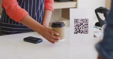 Video of hands of biracial waitress with payment terminal. coffee and bistro shop, running small independent business.