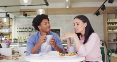 Video of happy diverse woman and man drinking and talking at coffee shop. coffee and bistro shop, running small independent business.