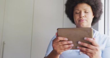 Video of focused plus size african american female doctor using tablet. health, medicine and doctor profession.