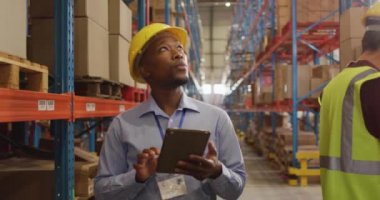 Depoda miğferi tablet kullanan Afro-Amerikan erkek işçi. küresel iş, nakliyat ve teslimat.