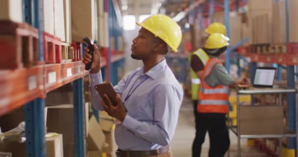 Αφροαμερικάνος Εργάτης Κράνος Που Χρησιμοποιεί Smartphone Στην Αποθήκη Παγκόσμιες Επιχειρήσεις — Αρχείο Βίντεο