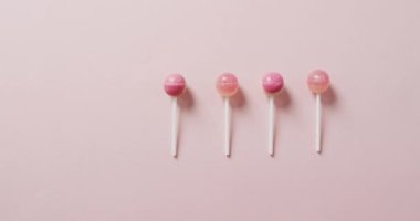 Pembe arka planda pembe lolipopların videosu. Renkli yemek, şeker, abur cubur ve tatlı konsepti.