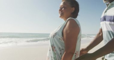 Güneşli plajda kucaklaşan gülümseyen Afrikalı Amerikalı bir çiftin portresi. sağlıklı, aktif emeklilik plaj tatili.