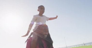 Mutlu Afro-Amerikan baba ve oğlunun güneşli bir günde eğlendiği bir video. Aile, birliktelik, birlikte dışarıda kaliteli zaman geçirmek..