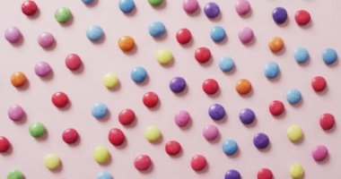 Pembe arka planda renkli mercimeklerin videosu. Renkli yemek, şeker, abur cubur ve tatlı konsepti.