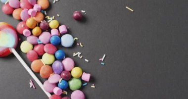 Renkli mercimek ve gri arka planda lolipop videosu. Renkli yemek, şeker, abur cubur ve tatlı konsepti.