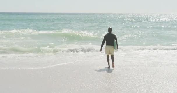 Ανώτερος Αφροαμερικάνος Που Περπατάει Σανίδα Του Σερφ Στην Ηλιόλουστη Παραλία — Αρχείο Βίντεο