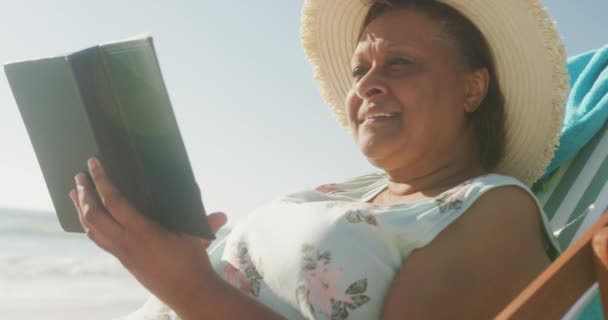 Lachende Senior Afrikaans Amerikaanse Vrouw Liggend Zonnebank Boek Aan Het — Stockvideo