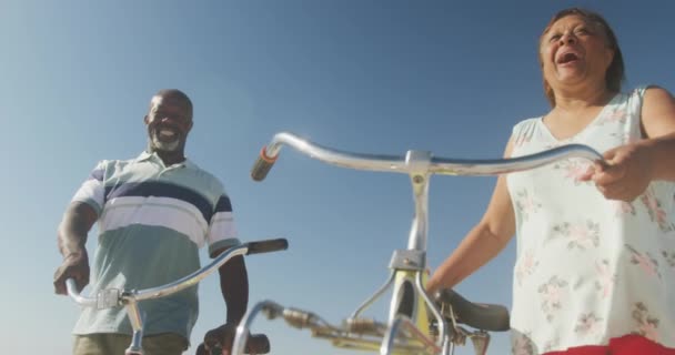 在阳光灿烂的海滩上骑自行车散步的老非洲裔美国夫妇笑着 积极的退休海滩假期 — 图库视频影像