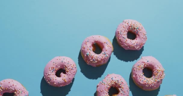 蓝色背景上涂有糖霜的甜甜圈录像 五彩缤纷的食物 小吃和糖果概念 — 图库视频影像