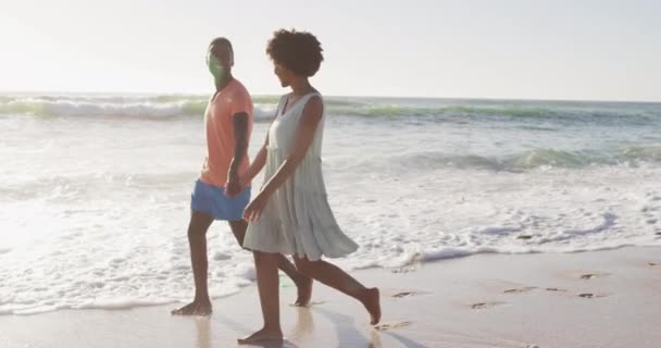 アフリカ系アメリカ人のカップルが手を取り合い 日当たりの良いビーチを歩く笑顔 健康的で活動的な家族のビーチホリデー — ストック動画