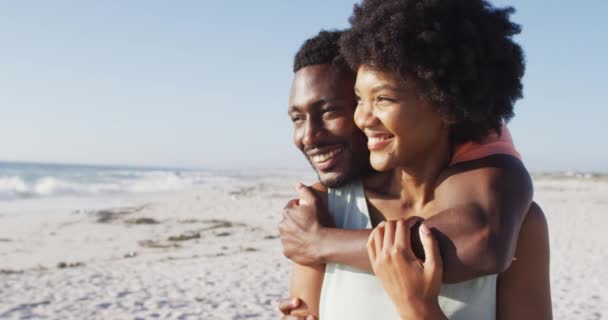 笑容可亲的非洲裔美国夫妇拥抱并远眺阳光明媚的海滩 积极的家庭海滩假期 — 图库视频影像