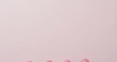 Pembe arka planda pembe lolipopların videosu. Renkli yemek, şeker, abur cubur ve tatlı konsepti.