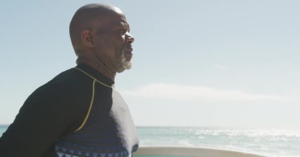 Portret Uśmiechniętego Starszego Afrykanina Chodzącego Deską Surfingową Słonecznej Plaży Zdrowe — Wideo stockowe