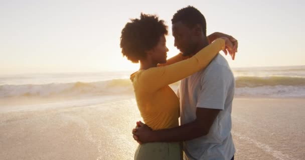 在阳光灿烂的海滩上拥抱在水里的一对非洲裔美国夫妇 积极的家庭海滩假期 — 图库视频影像