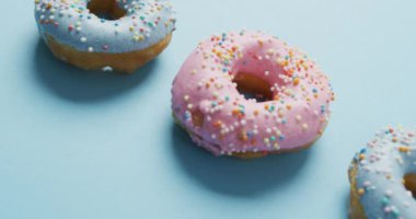 Mavi arka planda kremalı donut videosu. Renkli yemek, şeker, abur cubur ve tatlı konsepti.