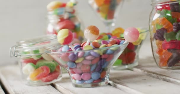 木製のテーブルの上にガラス容器でカラフルな様々なお菓子のビデオ カラフルな楽しい食べ物 お菓子 お菓子のコンセプト — ストック動画