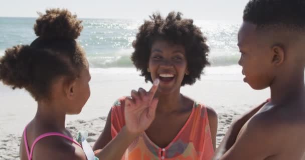 晴れたビーチでサンクリームを使用してアフリカ系アメリカ人の家族を笑顔 健康的で活動的な家族のビーチホリデー — ストック動画