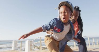 Mutlu Afro-Amerikan babasının oğluna gezinti güvertesinde kaykay yapmayı öğretirken videosu. Aile, birliktelik, birlikte dışarıda kaliteli zaman geçirmek..