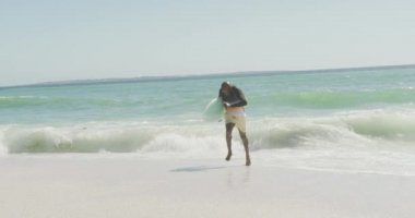 Sunny Beach 'te sörf tahtasıyla koşan kıdemli Afro-Amerikan adam. sağlıklı, aktif emeklilik plaj tatili.