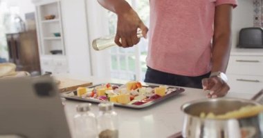 Video of midsection of african american woman preparing meal in kitchen. lifestyle, household, spending free time at home.