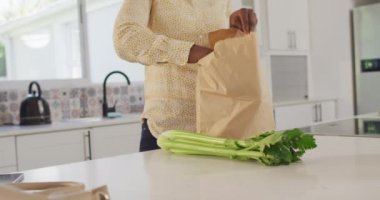 Afro-Amerikan bir kadının mutfak poşetlerini açarken videosu. Yaşam tarzı, ev hayatı, evde boş zaman geçirmek..