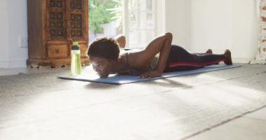 Video of african american woman practicing yoga at home. active healthy lifestyle, exercising at home.
