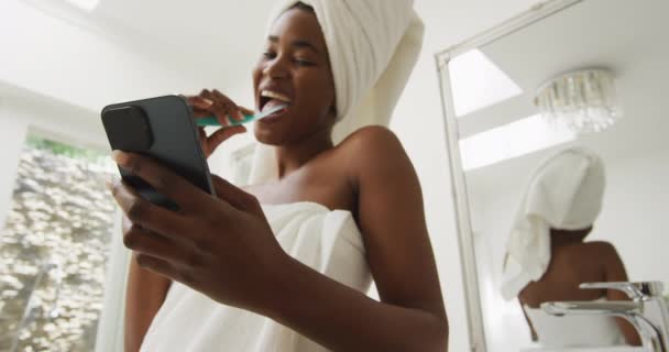 Video Happy African American Woman Robe Brushing Teeth Using Smartphone — Stockvideo