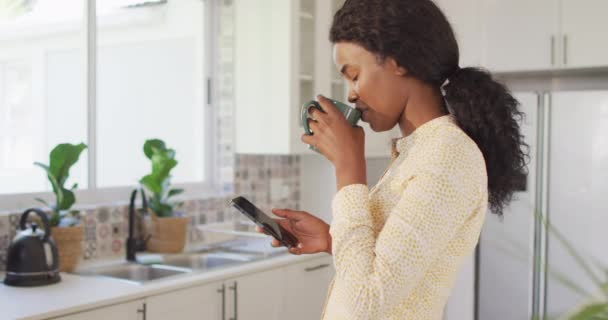 Video African American Woman Drinking Coffee Using Smartphone Kitchen Leisure — Videoclip de stoc