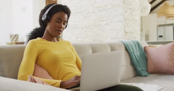 Video Glad Afrikansk Amerikansk Kvinde Sofa Med Hovedtelefoner Ved Hjælp – Stock-video