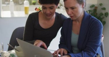 Evinde dizüstü bilgisayarla karısını öperken beyaz bir kadın. lgbt ilişkisi ve yaşam tarzı konsepti