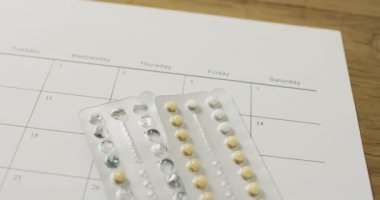 Tahta masadaki takvim üzerinden sarı tabletlerin yakın çekim videosu. küresel tıp ve sağlık konsepti.