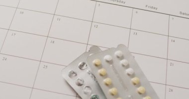 Beyaz takvim üzerinden sarı tabletlerin yakın çekim videosu. küresel tıp ve sağlık konsepti.