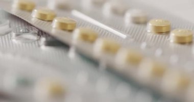 Video of close up of yellow tablets on pink background. global medicine and healthcare concept.