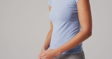 Beyaz arka planda karnına dokunan melez kadının videosu. küresel tıp ve sağlık konsepti.