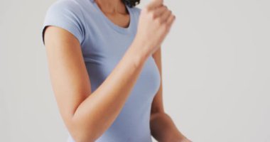 Beyaz arka planda dirseğine dokunan melez bir kadının videosu. küresel tıp ve sağlık konsepti.