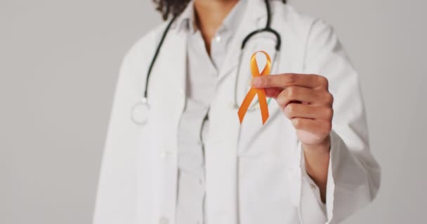 Video Smiling Biracial Female Doctor Holding Orange Kidney Cancer Ribbon — стоковое видео