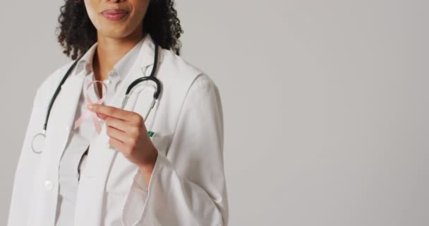 Video Smiling Biracial Female Doctor Holding Pink Breast Cancer Ribbon — Stok video