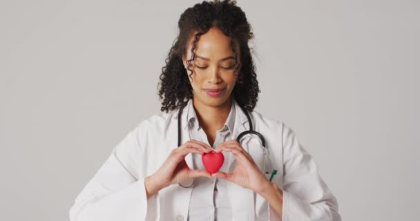 Video Portrait Smiling Biracial Female Doctor Holding Heart White Background — Stock Video