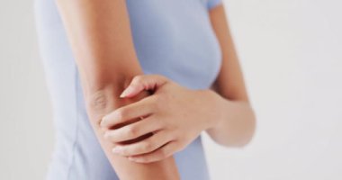 Beyaz arka planda koluna dokunan melez kadının videosu. küresel tıp ve sağlık konsepti.