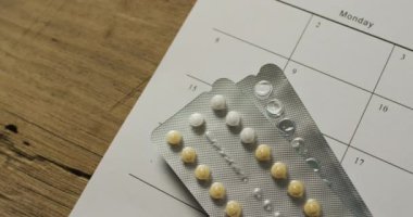 Tahta masadaki takvim üzerinden sarı tabletlerin yakın çekim videosu. küresel tıp ve sağlık konsepti.