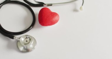 Video of close up of stethoscope with heart on pink background. global medicine and healthcare concept.