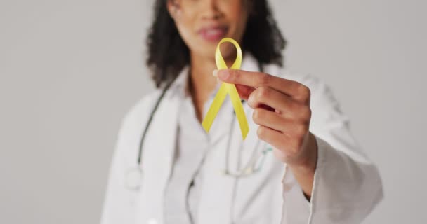 Video Smiling Biracial Female Doctor Holding Yellow Bladder Cancer Ribbon — ストック動画