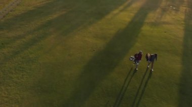Güneşli bir günde golf sahasında yürüyen iki farklı erkek golfçü. sağlıklı ve aktif zaman.