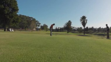 Güneşli bir günde golf sahasında golf oynayan iki farklı erkek golfçü. sağlıklı ve aktif zaman.