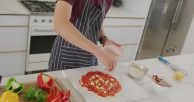 Asian male teenager preparing food and wearing apron in kitchen. spending time alone at home.