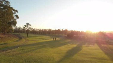 Güneşli bir günde golf sahasında yürüyen iki farklı erkek golfçü. sağlıklı ve aktif zaman.