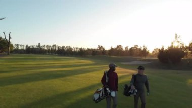 Güneşli bir günde golf sahasında yürüyen iki farklı erkek golfçü. sağlıklı ve aktif zaman.