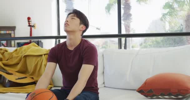 Azjatycki Nastolatek Ogląda Telewizję Koszykówką Siedzi Salonie Spędzać Czas Samotnie — Wideo stockowe